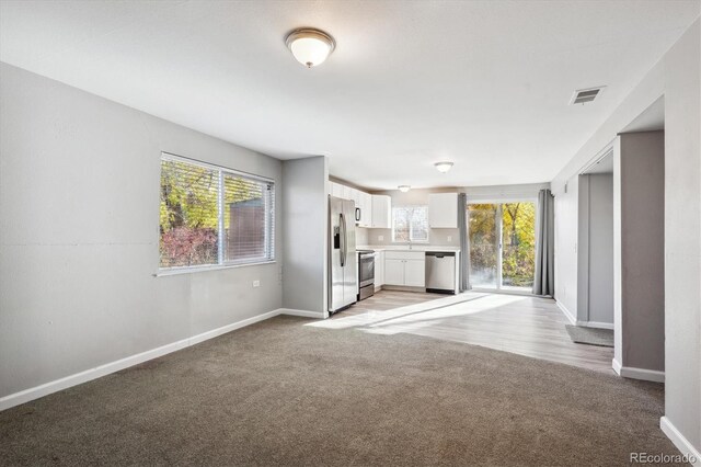 3900 Turnpike Dr, Westminster, CO 80030 - unfurnished living room featuring baseboards, light carpet, and visible vents