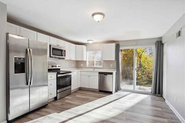 3900 Turnpike Dr, Westminster, CO 80030 - kitchen featuring white cabinets, light wood-style floors, light countertops, stainless steel appliances, and visible vents