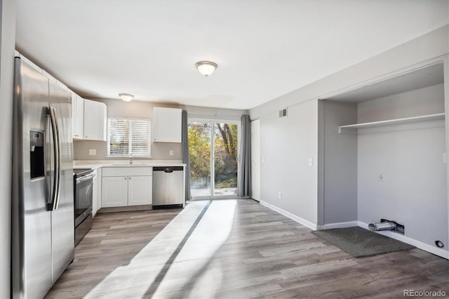 3900 Turnpike Dr, Westminster, CO 80030 - kitchen with light countertops, white cabinets, light wood-style floors, and stainless steel appliances