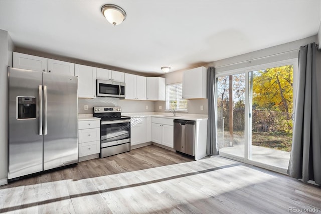 3900 Turnpike Dr, Westminster, CO 80030 - kitchen featuring appliances with stainless steel finishes, a sink, light wood-style floors, light countertops, and white cabinetry