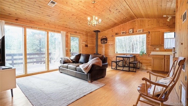 living room with wood walls, a wood stove, wooden ceiling, vaulted ceiling, and light hardwood / wood-style flooring