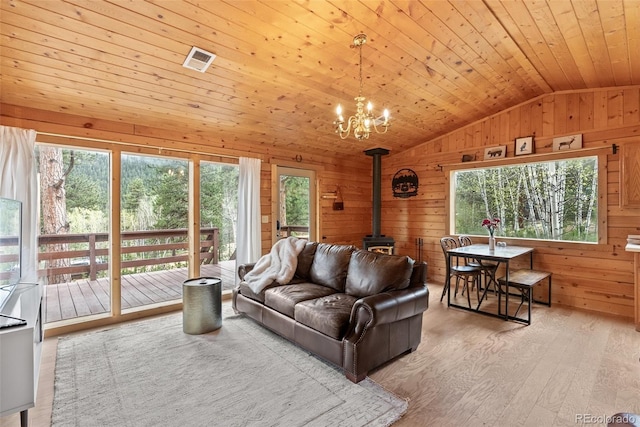 339 Hall Rd, Bailey, CO 80421 - living area featuring vaulted ceiling, a wood stove, wood walls, a chandelier, and wood finished floors