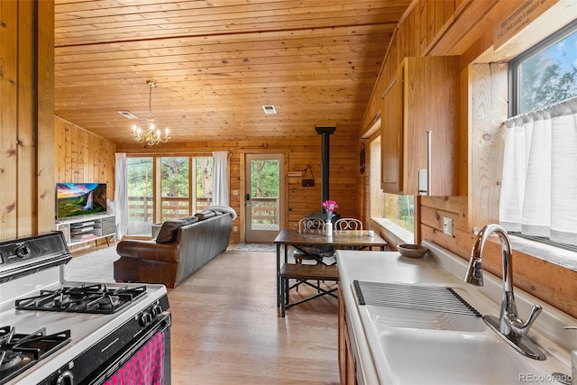 339 Hall Rd, Bailey, CO 80421 - kitchen with white range with gas cooktop, plenty of natural light, a wood stove, wooden walls, and a chandelier