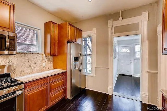 1365 Clayton St, Denver, CO 80206 - kitchen featuring stainless steel appliances, dark wood-style flooring, brown cabinetry, and decorative backsplash