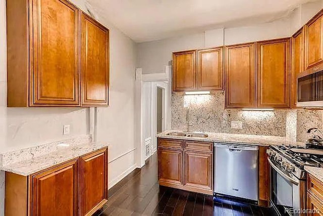 1365 Clayton St, Denver, CO 80206 - kitchen with appliances with stainless steel finishes, a sink, dark wood finished floors, brown cabinets, and light stone countertops