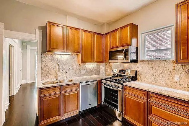 1365 Clayton St, Denver, CO 80206 - kitchen with stainless steel appliances, a sink, dark wood-style flooring, brown cabinetry, and tasteful backsplash