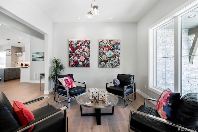 living room featuring sink, a notable chandelier, and light wood-type flooring