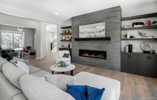 living room with built in shelves, a tile fireplace, and light wood-type flooring