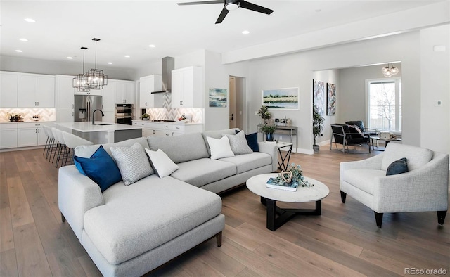 living room with sink, hardwood / wood-style flooring, and ceiling fan with notable chandelier