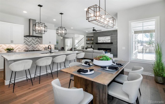 dining room featuring ceiling fan, a fireplace, sink, and wood-type flooring