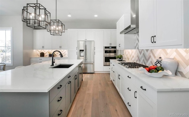 kitchen with appliances with stainless steel finishes, sink, a kitchen island with sink, and white cabinets