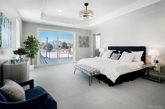 bedroom featuring carpet floors, a tray ceiling, and access to outside