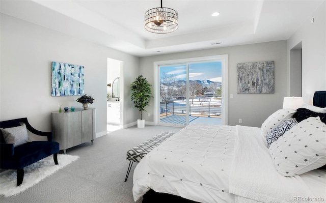 bedroom featuring access to exterior, a tray ceiling, and light colored carpet