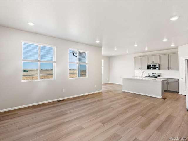 unfurnished living room featuring recessed lighting, baseboards, and light wood-style flooring