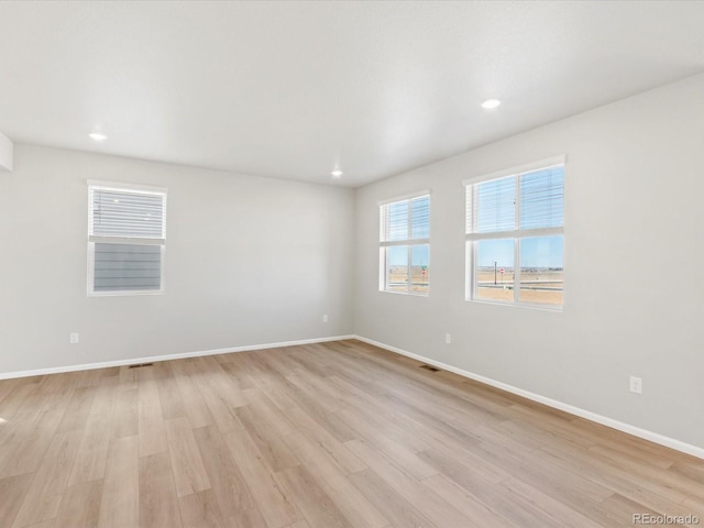 spare room with recessed lighting, light wood-type flooring, baseboards, and visible vents