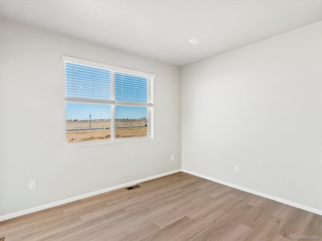 empty room featuring visible vents, baseboards, and wood finished floors