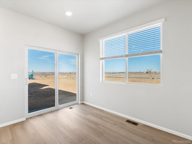 unfurnished room with visible vents, baseboards, and wood finished floors