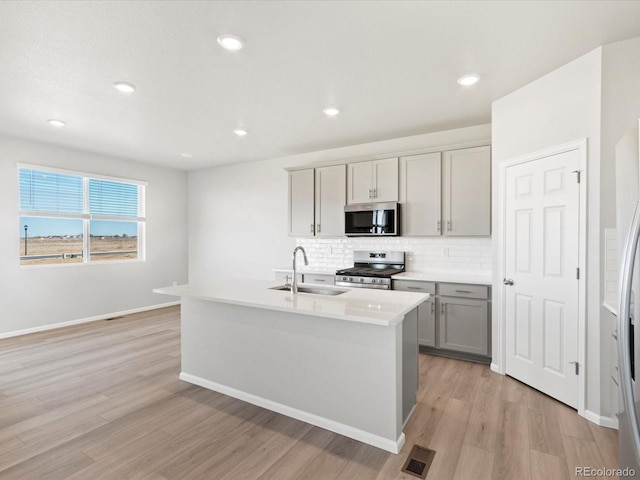 kitchen featuring visible vents, gray cabinets, a sink, appliances with stainless steel finishes, and decorative backsplash