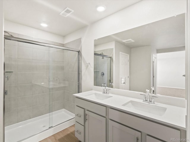 bathroom featuring a sink, visible vents, wood finished floors, and a stall shower