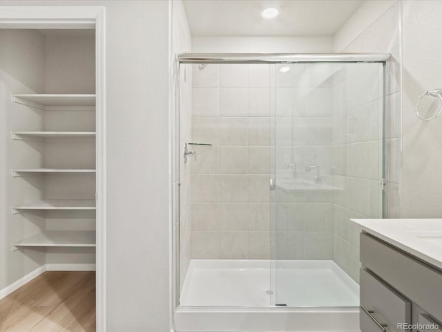 bathroom featuring baseboards, vanity, wood finished floors, and a shower stall