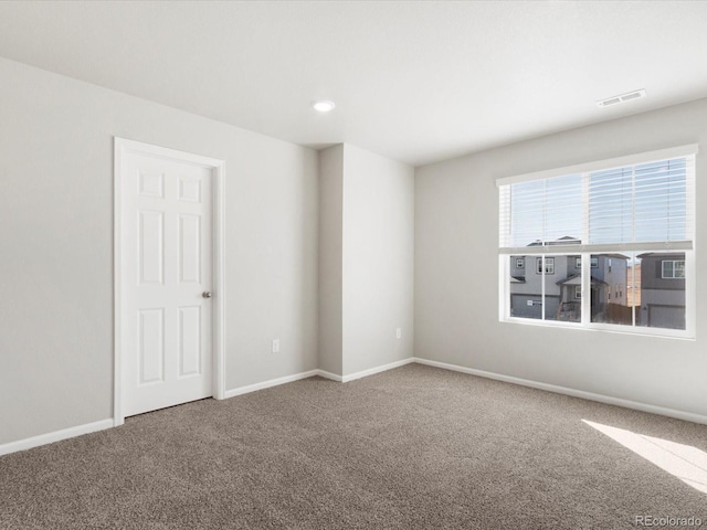 spare room with carpet flooring, baseboards, and visible vents