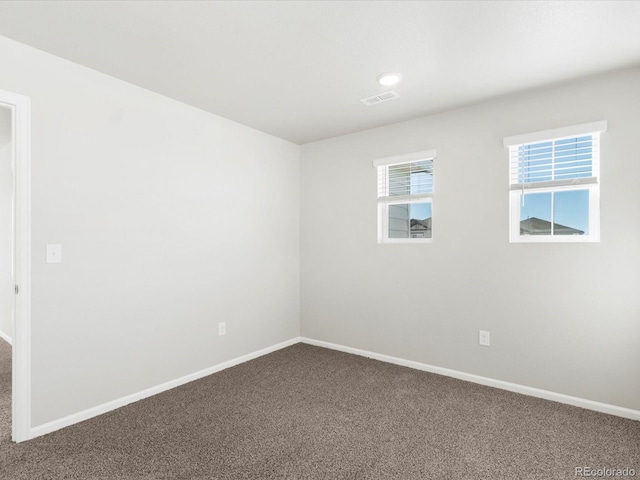 unfurnished room featuring baseboards, visible vents, and dark colored carpet