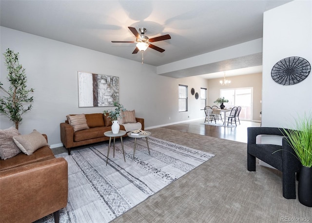 carpeted living room with ceiling fan with notable chandelier