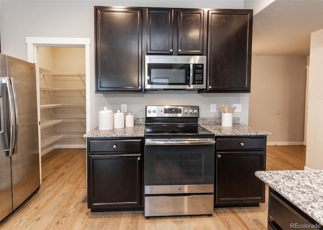 kitchen with light stone counters, light hardwood / wood-style floors, and appliances with stainless steel finishes