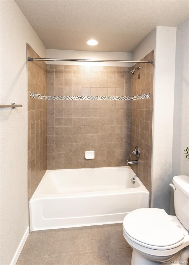 bathroom with tile patterned floors, tiled shower / bath combo, and toilet