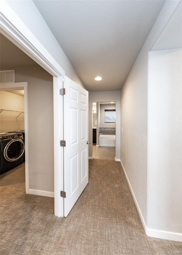 hall with washer / dryer and light colored carpet