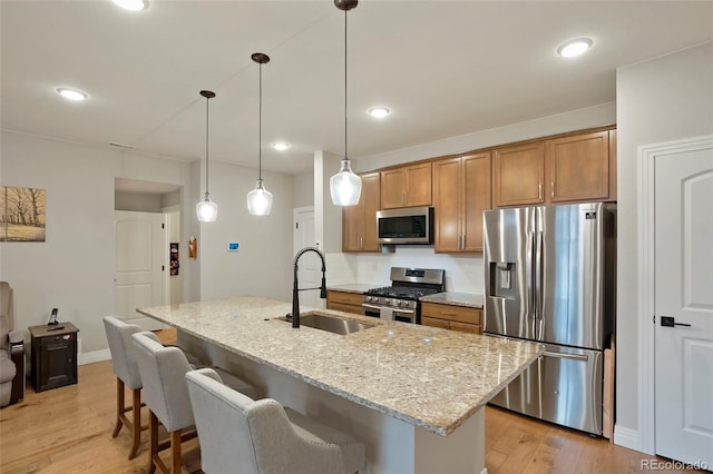 16461 E 119th Way Unit B, Commerce City, CO 80022 - kitchen featuring appliances with stainless steel finishes, a breakfast bar area, light wood-style floors, brown cabinetry, and recessed lighting