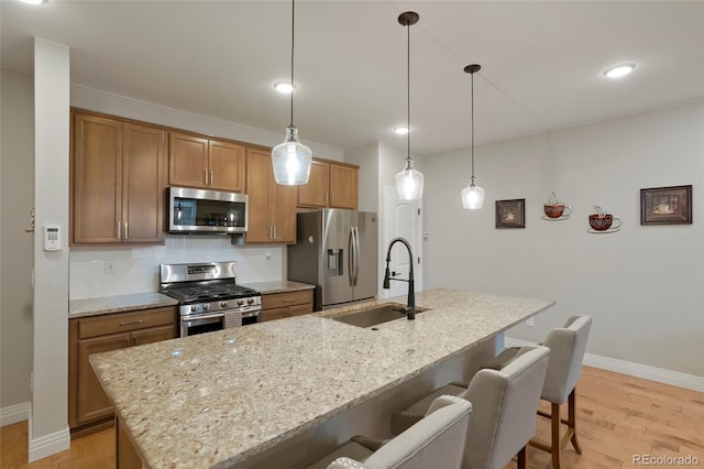16461 E 119th Way Unit B, Commerce City, CO 80022 - kitchen with stainless steel appliances, light wood-type flooring, a breakfast bar area, a center island with sink, and recessed lighting