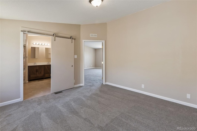 235 W May St, Cripple Creek, CO 80813 - unfurnished bedroom with carpet floors, a barn door, ensuite bathroom, and lofted ceiling