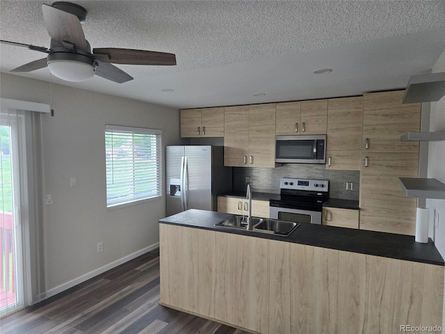 1265 S Biscay St, Aurora, CO 80017 - kitchen with stainless steel appliances, light brown cabinetry, a peninsula, dark wood finished floors, and a textured ceiling