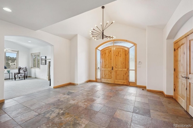 156 S Lookout Mountain Rd, Golden, CO 80401 - foyer entrance featuring baseboards, arched walkways, stone tile flooring, vaulted ceiling, and a chandelier