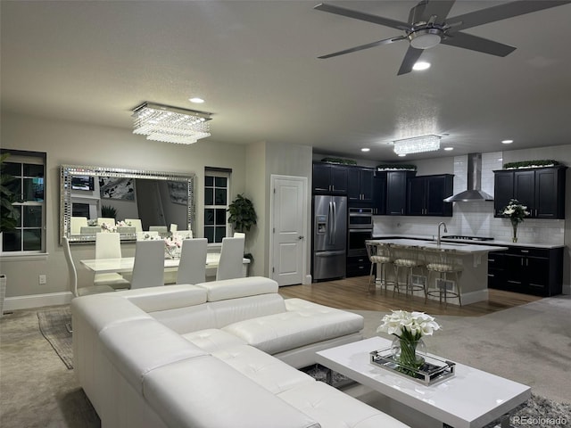 living room with ceiling fan with notable chandelier, hardwood / wood-style flooring, and sink