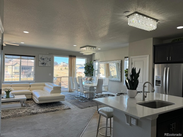 kitchen with stainless steel refrigerator with ice dispenser, a textured ceiling, and sink