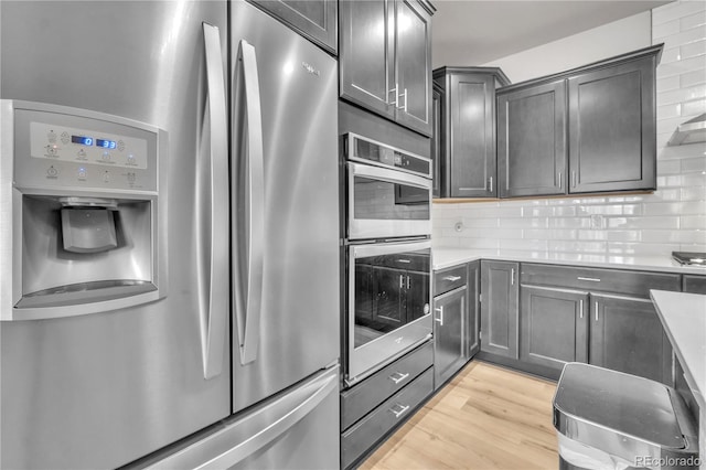 kitchen with stainless steel appliances, light wood-type flooring, and decorative backsplash