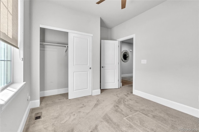 unfurnished bedroom with light colored carpet, ceiling fan, and a closet