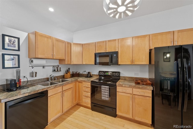 kitchen with light brown cabinetry, black appliances, light wood-type flooring, and a sink