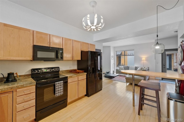 kitchen with light brown cabinets, black appliances, tile counters, light wood-style floors, and pendant lighting