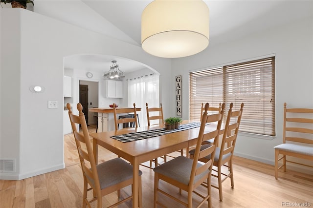 dining room with light hardwood / wood-style flooring, a chandelier, and lofted ceiling