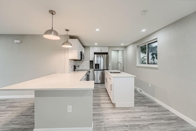 kitchen featuring sink, appliances with stainless steel finishes, white cabinetry, hanging light fixtures, and tasteful backsplash