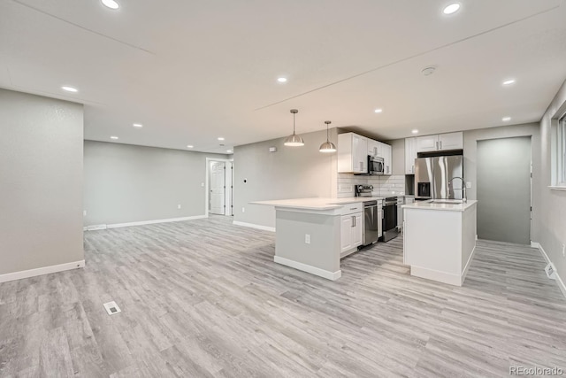 kitchen featuring pendant lighting, stainless steel appliances, a center island, tasteful backsplash, and white cabinets