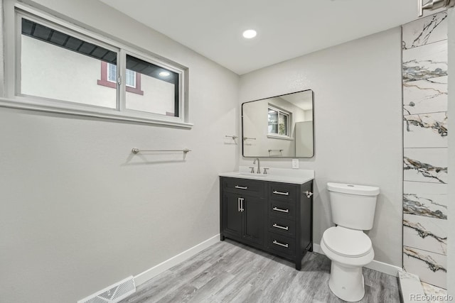 bathroom featuring vanity, wood-type flooring, plenty of natural light, and toilet