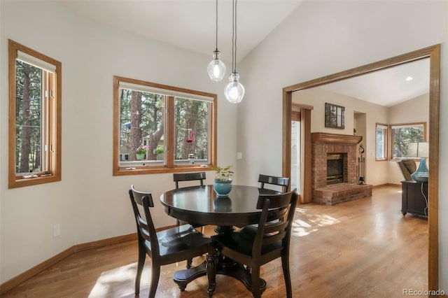 19165 Golden Arrow Cir, Monument, CO 80132 - dining room with lofted ceiling, light wood finished floors, and a fireplace