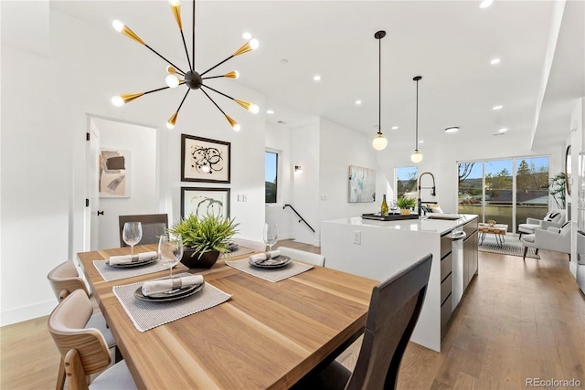 dining space featuring light hardwood / wood-style flooring, a notable chandelier, and sink