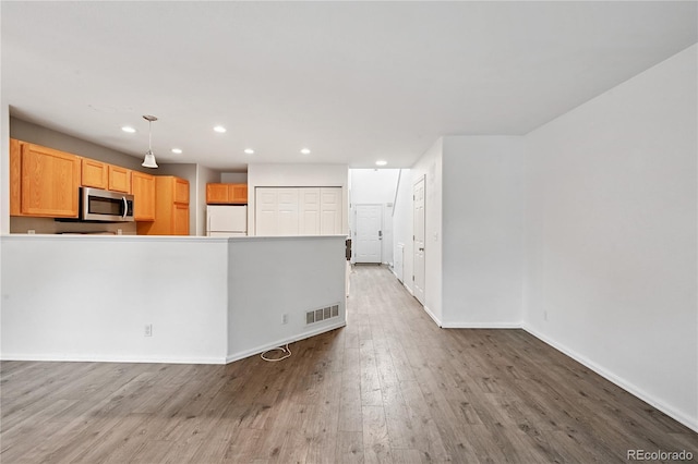 2085 E 103rd Ave, Thornton, CO 80229 - kitchen with stainless steel microwave, freestanding refrigerator, recessed lighting, wood finished floors, and a peninsula