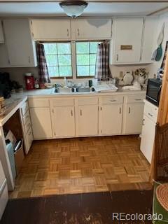 kitchen featuring light countertops, a sink, and white cabinets