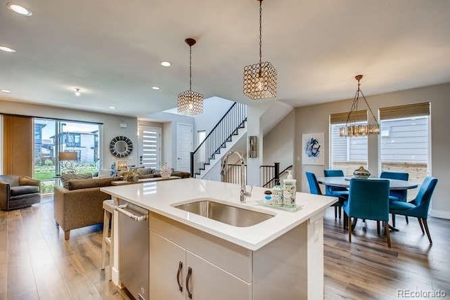 kitchen with a center island with sink, decorative light fixtures, stainless steel dishwasher, and sink